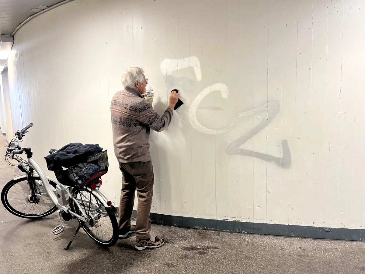 Ein Mann putzt ZSC-Schriftzug in einer Bahnhofsunterführung weg.
